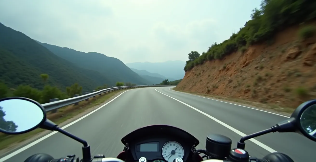 Vista desde el casco del motorista mirando hacia el punto de salida de una curva cerrada en carretera de montaña